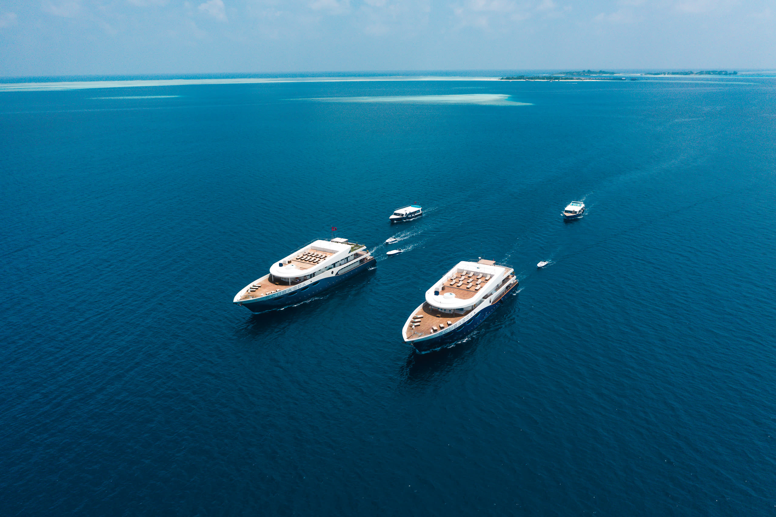 Scubaspa Yin and Yang at anchor in open water, each with its dive dhoni alongside